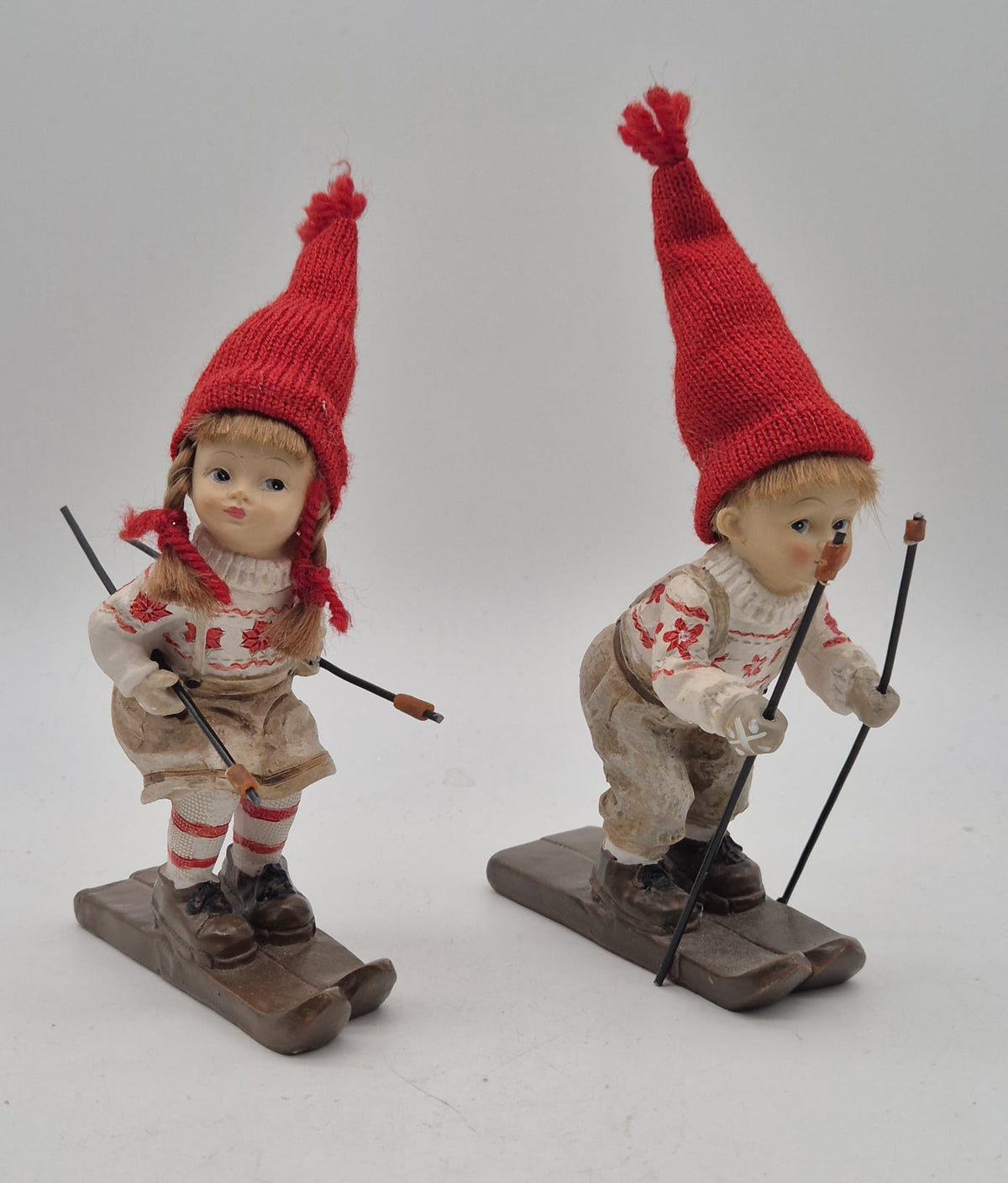 2 Winterkinder auf Skiern – Mädchen und Junge mit roten Strickmützen – Polyresin – ca. 16 cm