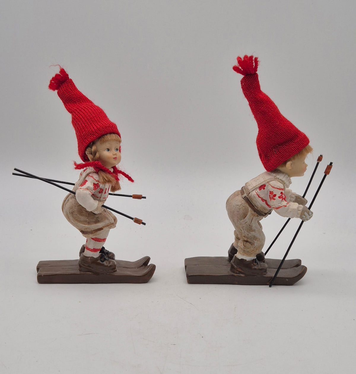 2 Winterkinder auf Skiern – Mädchen und Junge mit roten Strickmützen – Polyresin – ca. 16 cm