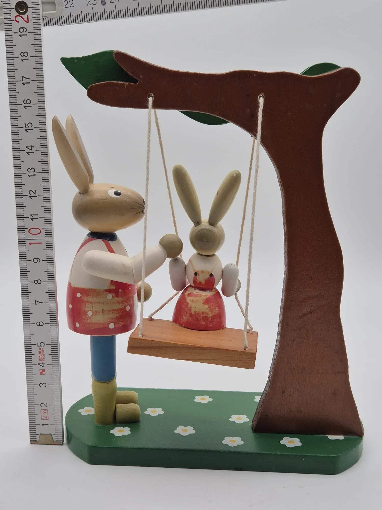 Hasenfigur Vater mit Kind auf Schaukel unter Baum Holz