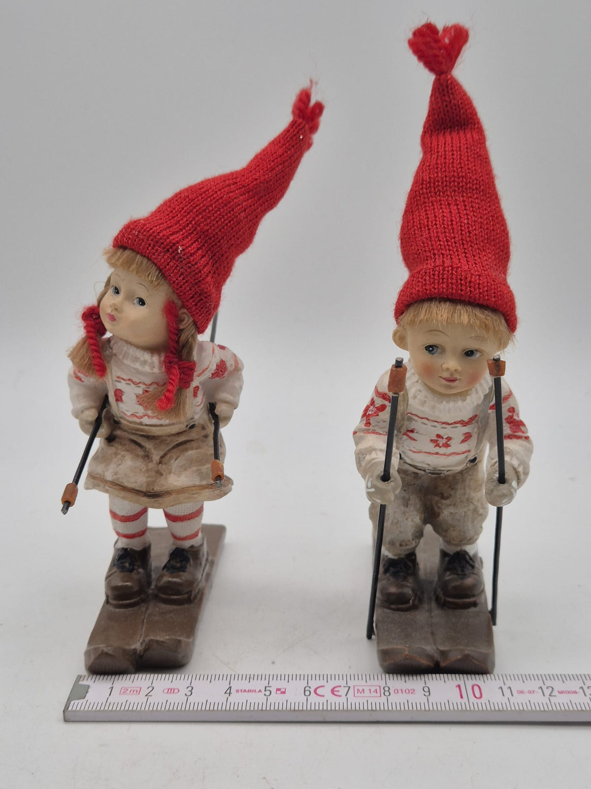 2 Winterkinder auf Skiern – Mädchen und Junge mit roten Strickmützen – Polyresin – ca. 16 cm
