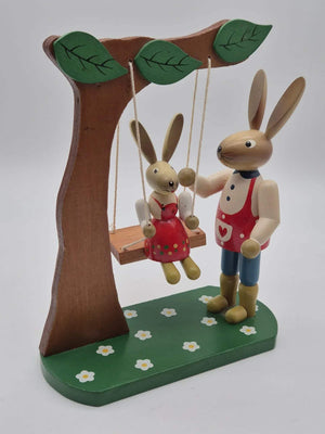 Hasenfigur Vater mit Kind auf Schaukel unter Baum Holz